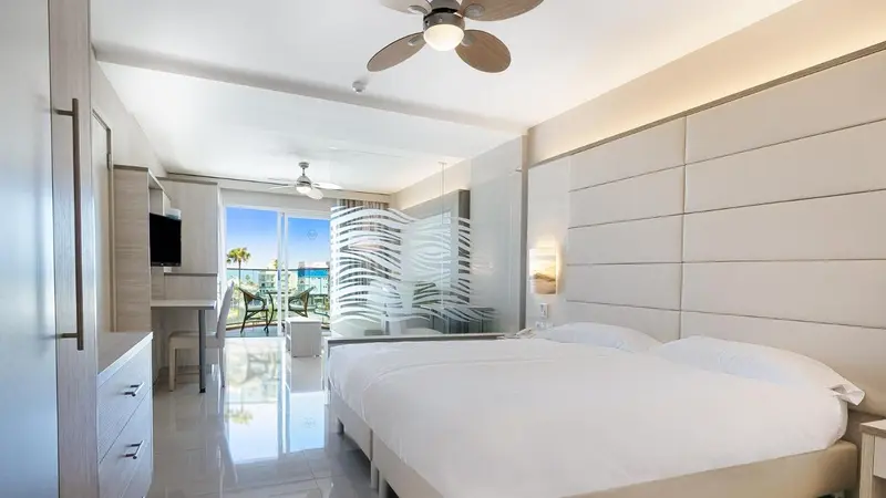 Chambre lumineuse avec un grand lit et vue sur la mer.
