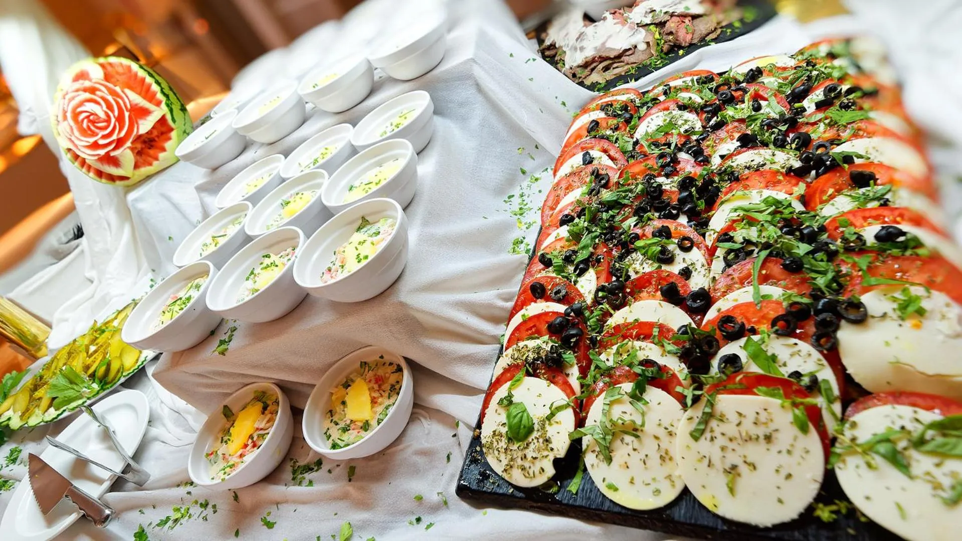 Un buffet propose une variété de salades, de viandes et de fruits sculptés.