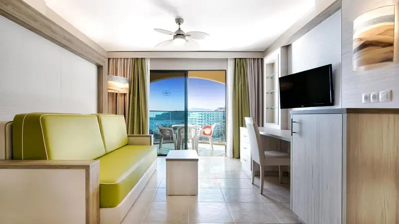 Espace de séjour lumineux avec canapé vert et vue sur la mer.
