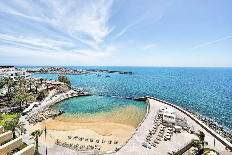 Vue aérienne d'une crique abritée avec une plage de sable et des transats.