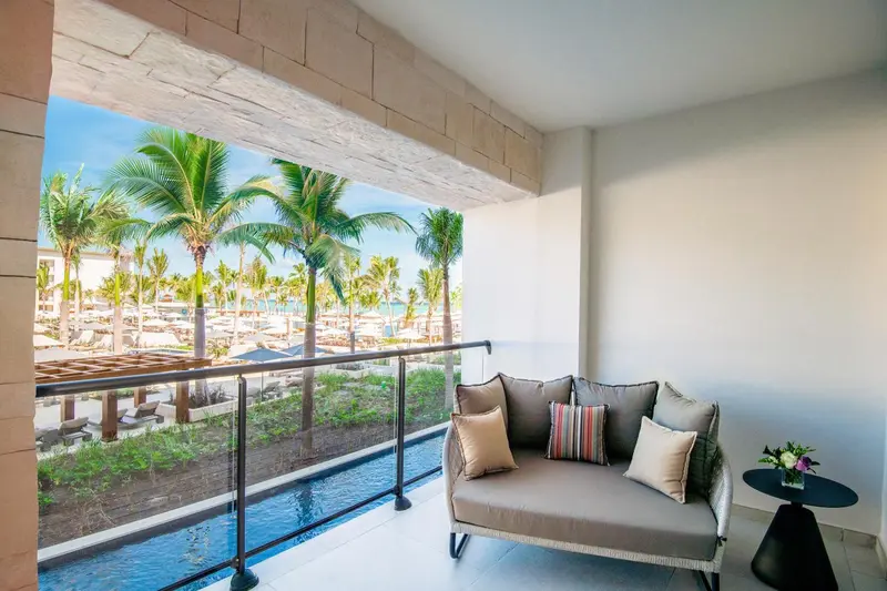 Canapé et coussins sur une terrasse avec vue sur la mer et la végétation.