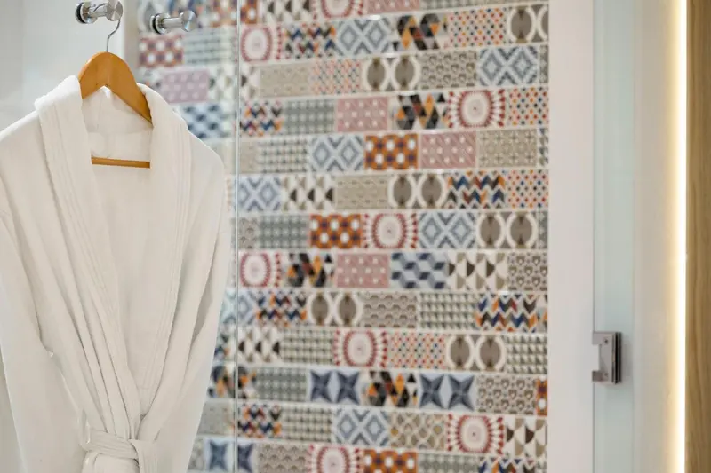 Peignoir blanc suspendu devant une porte vitrée décorée de motifs colorés.