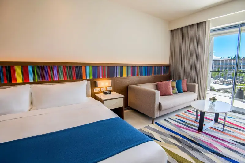Une chambre lumineuse avec un lit fait et un coin salon.