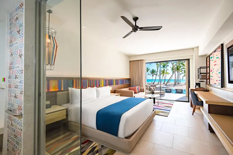 Chambre lumineuse avec un grand lit et vue sur la plage.