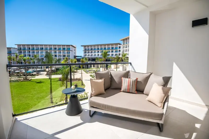 Un espace détente extérieur avec canapé et table basse offre une vue sur un complexe hôtelier.