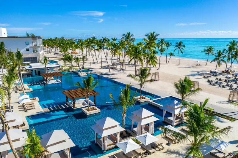 Vue aérienne d'un complexe hôtelier avec piscine et plage de sable blanc.