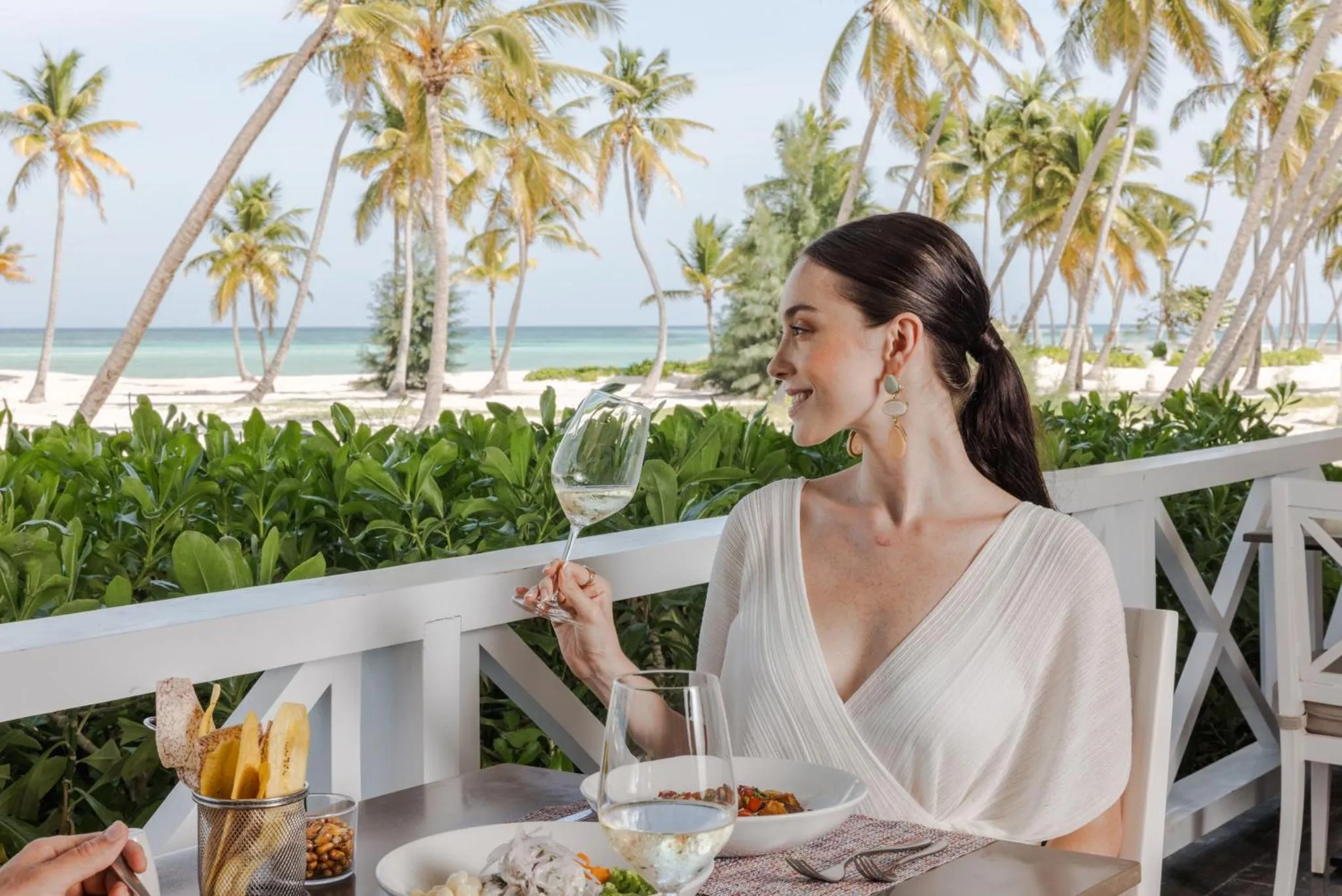 Une femme déguste une boisson sur une terrasse en bord de mer.