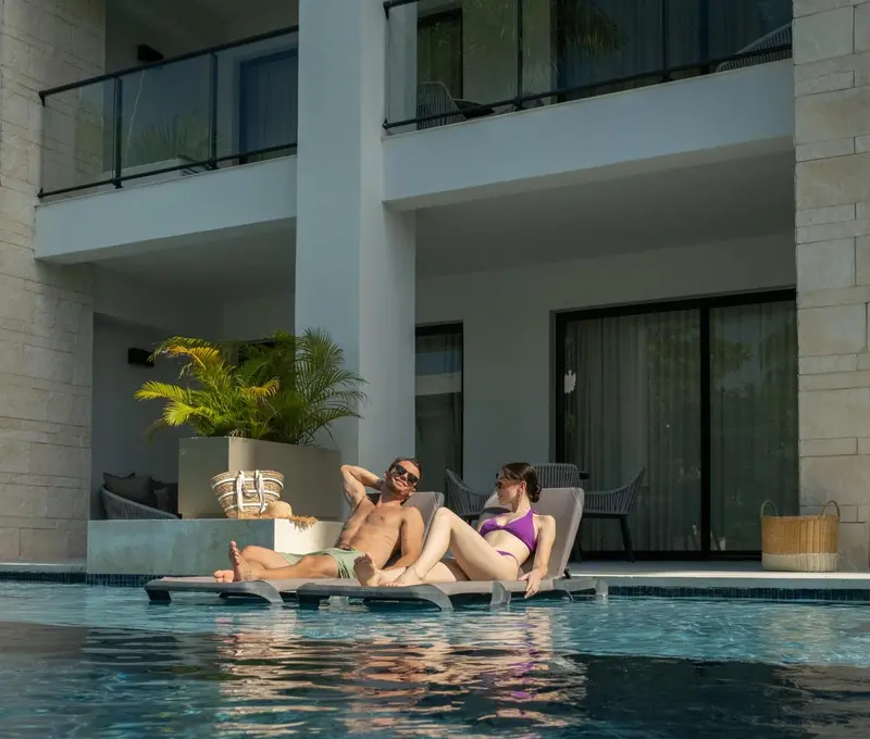 Un couple se relaxe sur des transats au bord d'une piscine.