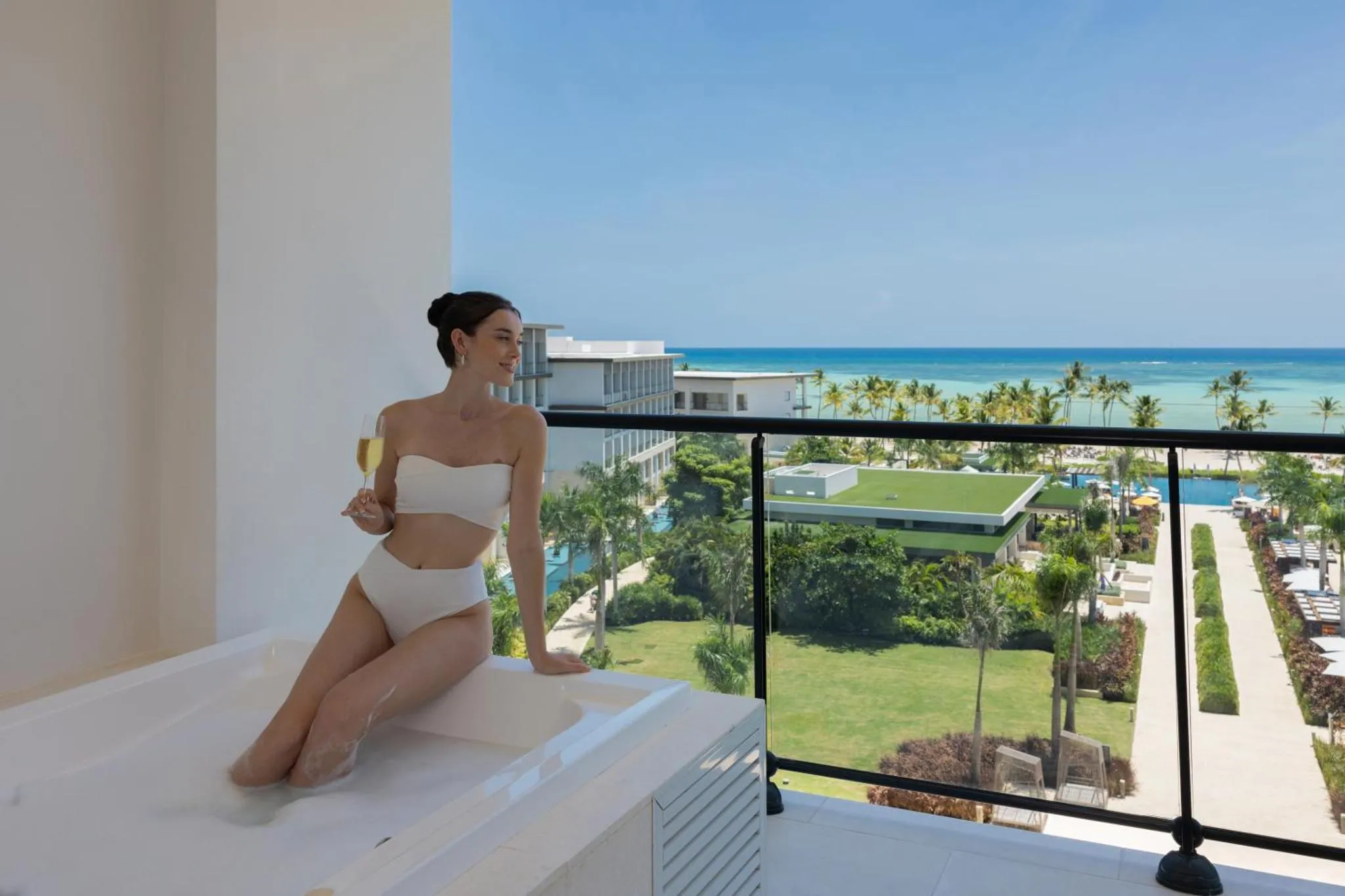 Une femme se détend dans un bain à remous sur une terrasse avec vue sur la mer.