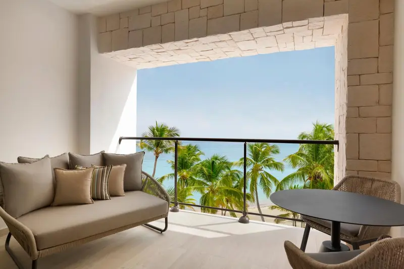 Canapé et table basse sur une terrasse avec vue sur la mer et la végétation.