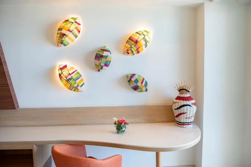 Une composition murale colorée illumine un coin repas avec une table et une chaise.
