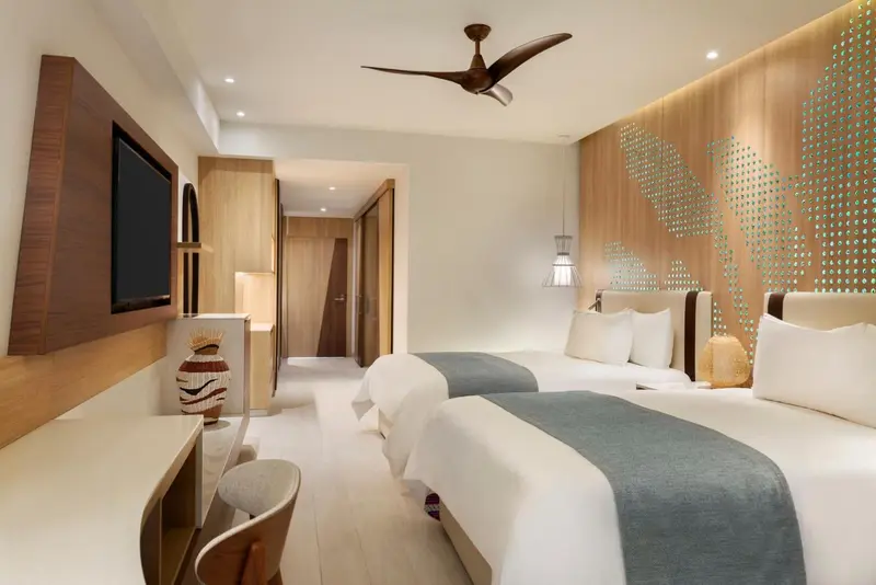 Une chambre lumineuse avec deux lits simples et un bureau.