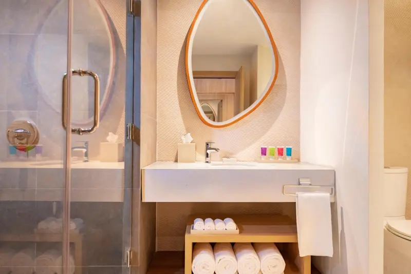 Une salle de bain moderne avec douche à l'italienne et miroir ovale.