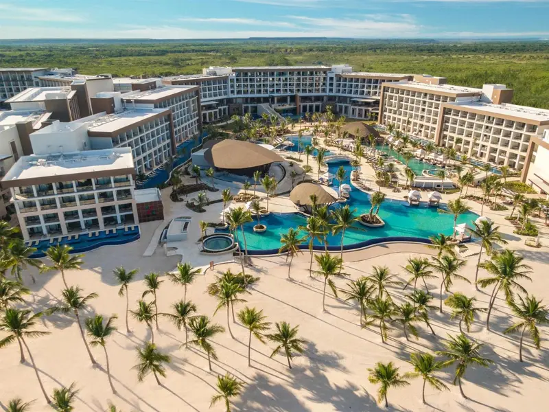 Vue aérienne d'un complexe hôtelier avec piscine et plage de sable blanc.