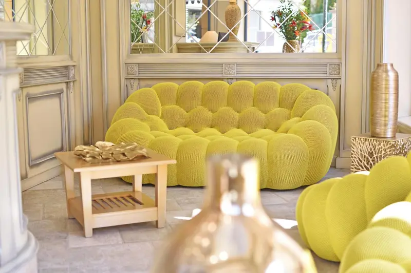 Un salon lumineux avec un canapé jaune et une table basse en bois.