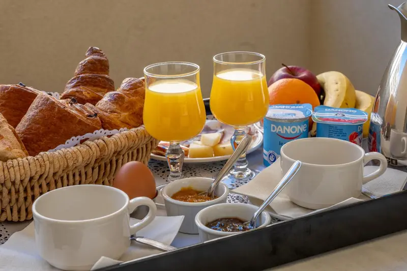 Un plateau de petit-déjeuner avec des viennoiseries, du jus d'orange et des yaourts.