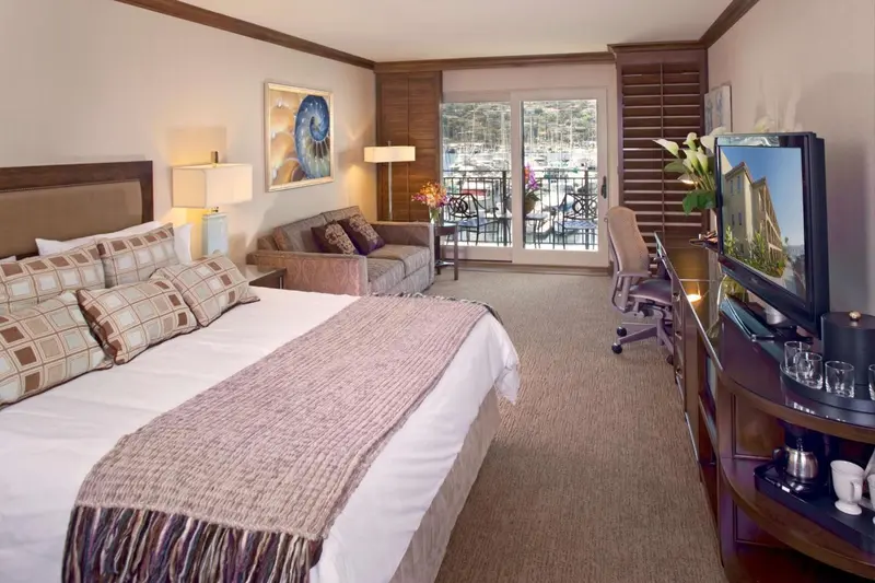 Une chambre lumineuse avec un grand lit et un coin salon donnant sur une terrasse.