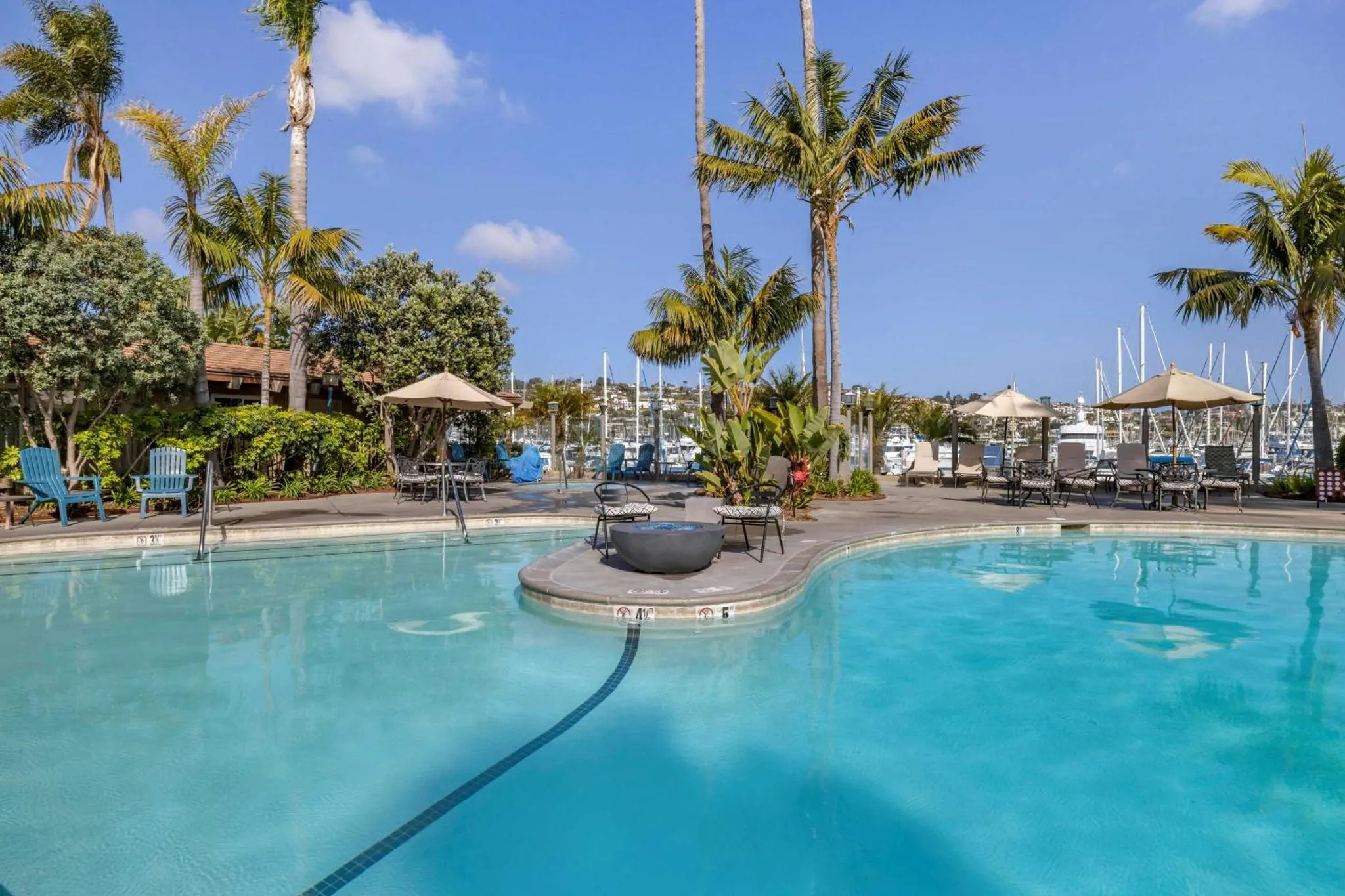 Une piscine turquoise entourée de végétation luxuriante et de transats.