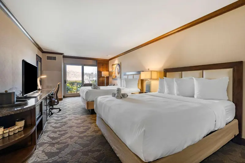 Chambre d'hôtel lumineuse avec deux lits et vue sur l'extérieur.