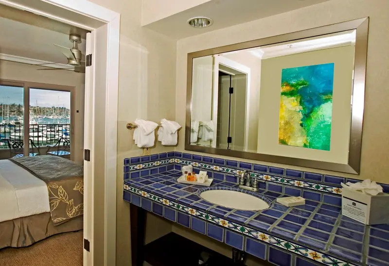 Une salle de bain lumineuse avec un grand miroir et des carreaux bleus.