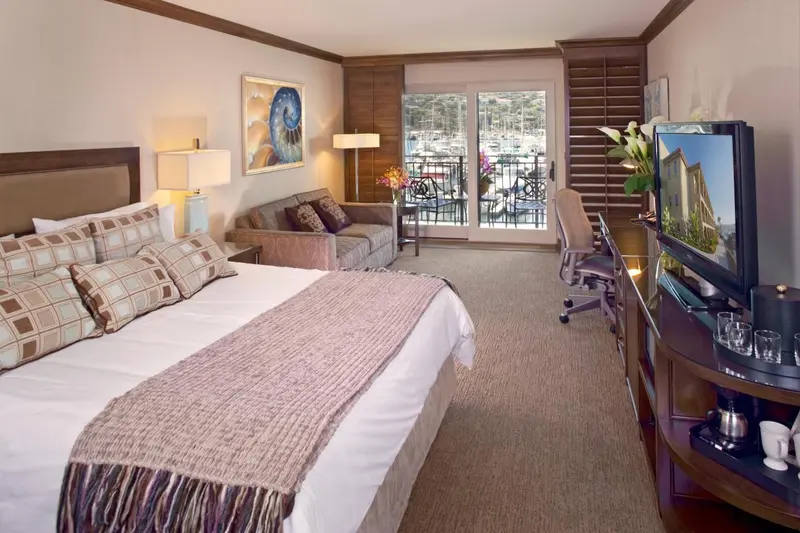 Une chambre lumineuse avec un grand lit et un coin salon donnant sur une terrasse.