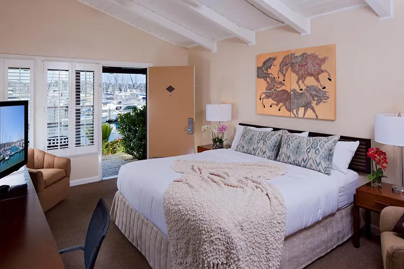 Une chambre lumineuse avec un grand lit et vue sur un port de plaisance.