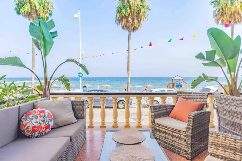 Espace de détente extérieur avec canapés et vue sur la mer.