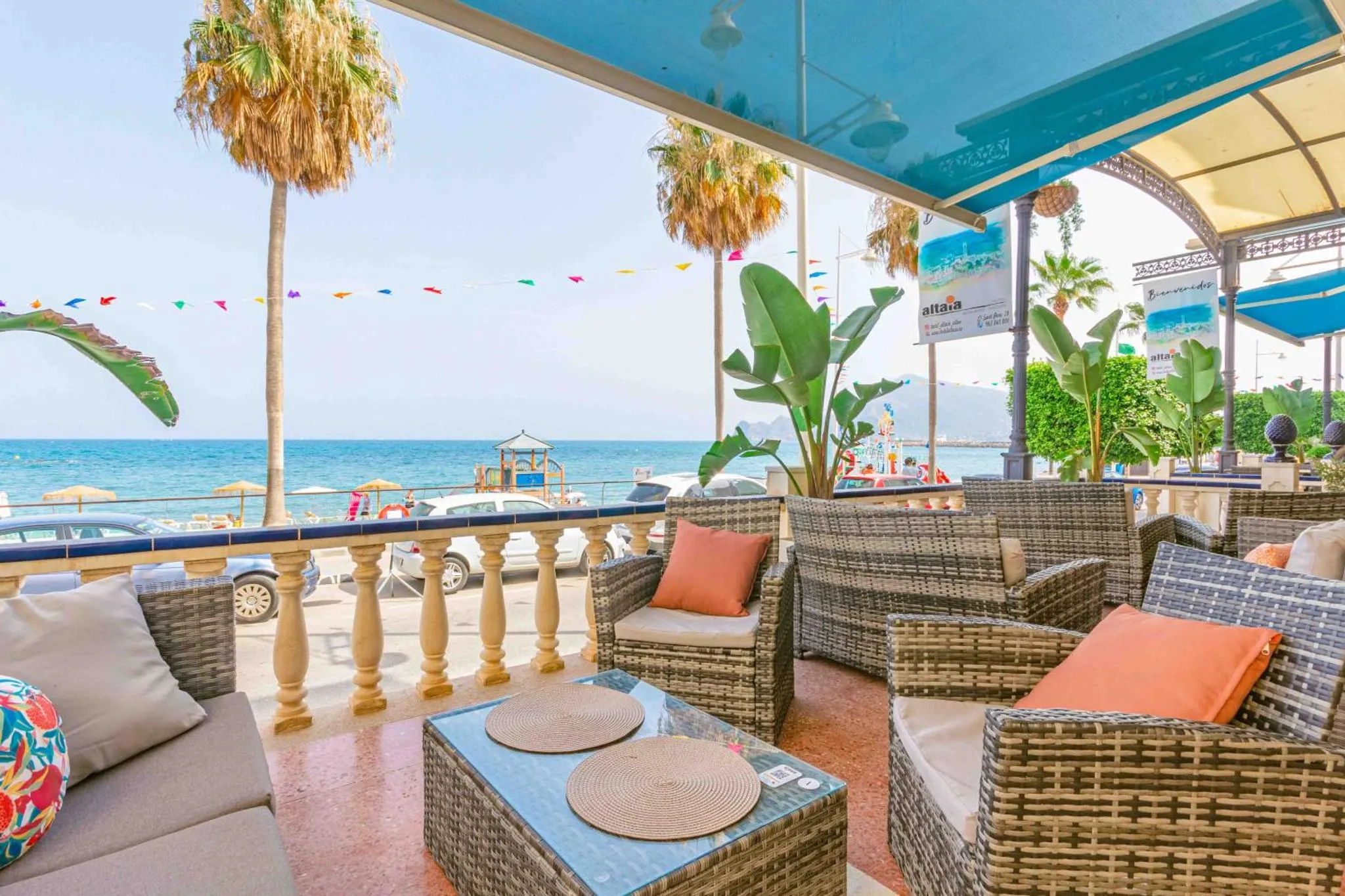 Terrasse ombragée avec mobilier en rotin donnant sur la mer.