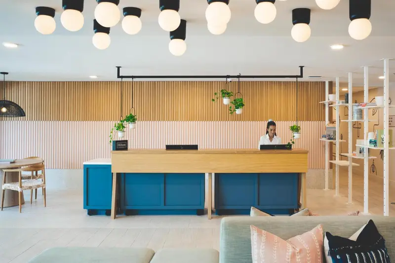 Une réception d'hôtel moderne avec un comptoir en bois et une décoration lumineuse.