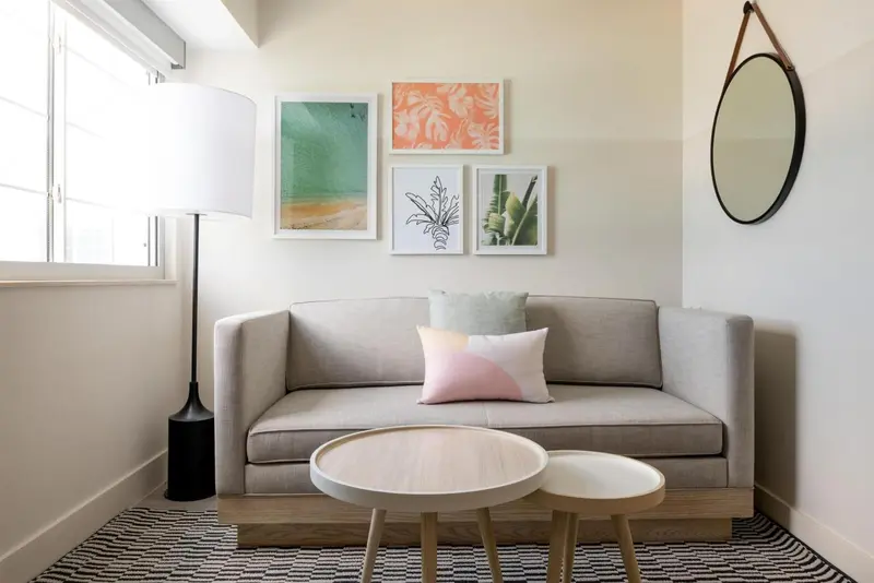 Un canapé gris et des coussins reposent devant un mur décoré de tableaux.