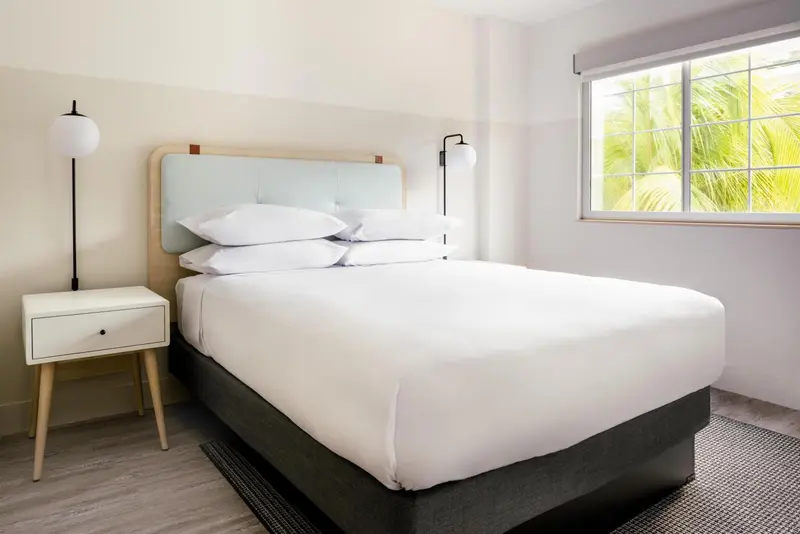 Une chambre lumineuse avec un grand lit recouvert de draps blancs.