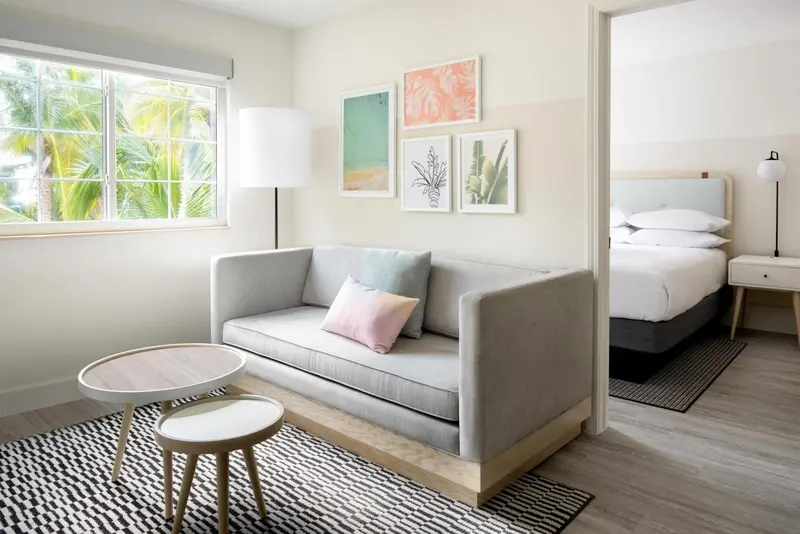 Un salon clair avec un canapé gris et des tableaux décoratifs.