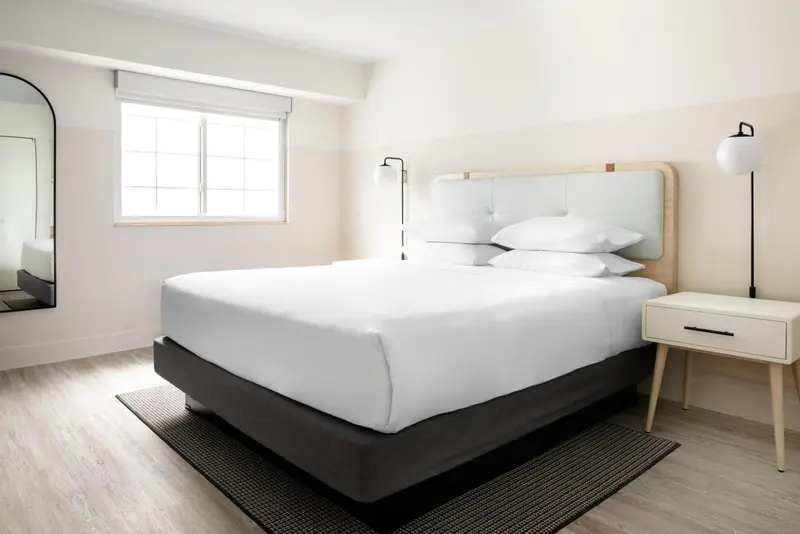 Une chambre lumineuse avec un grand lit recouvert de linge blanc.
