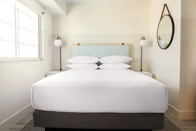 Une chambre lumineuse avec un grand lit recouvert d'oreillers blancs.