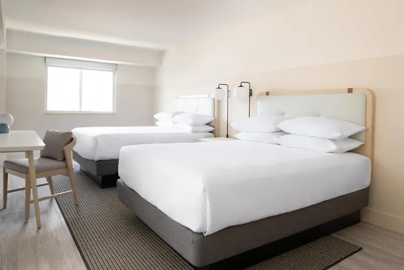 Une chambre d'hôtel lumineuse avec deux lits simples et un bureau.