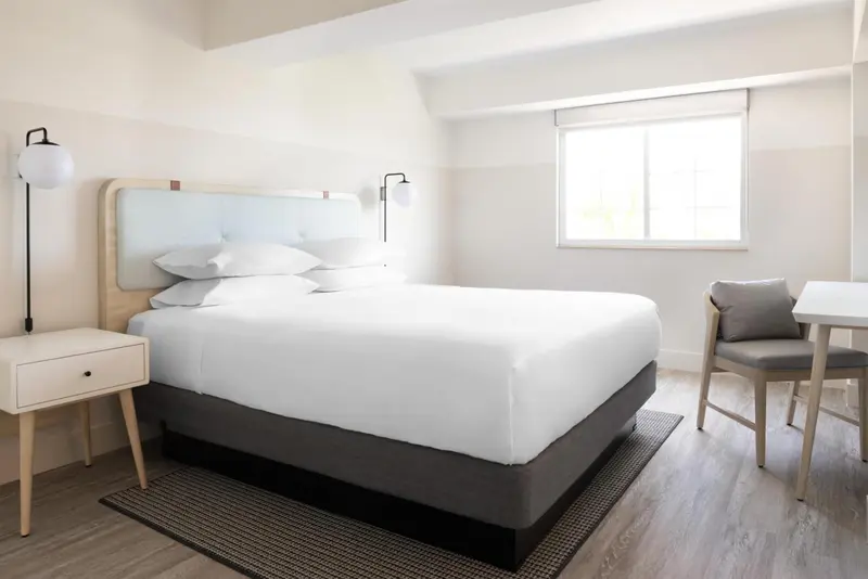 Une chambre lumineuse avec un grand lit et un espace bureau.