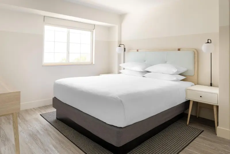 Une chambre lumineuse avec un grand lit recouvert de draps blancs.
