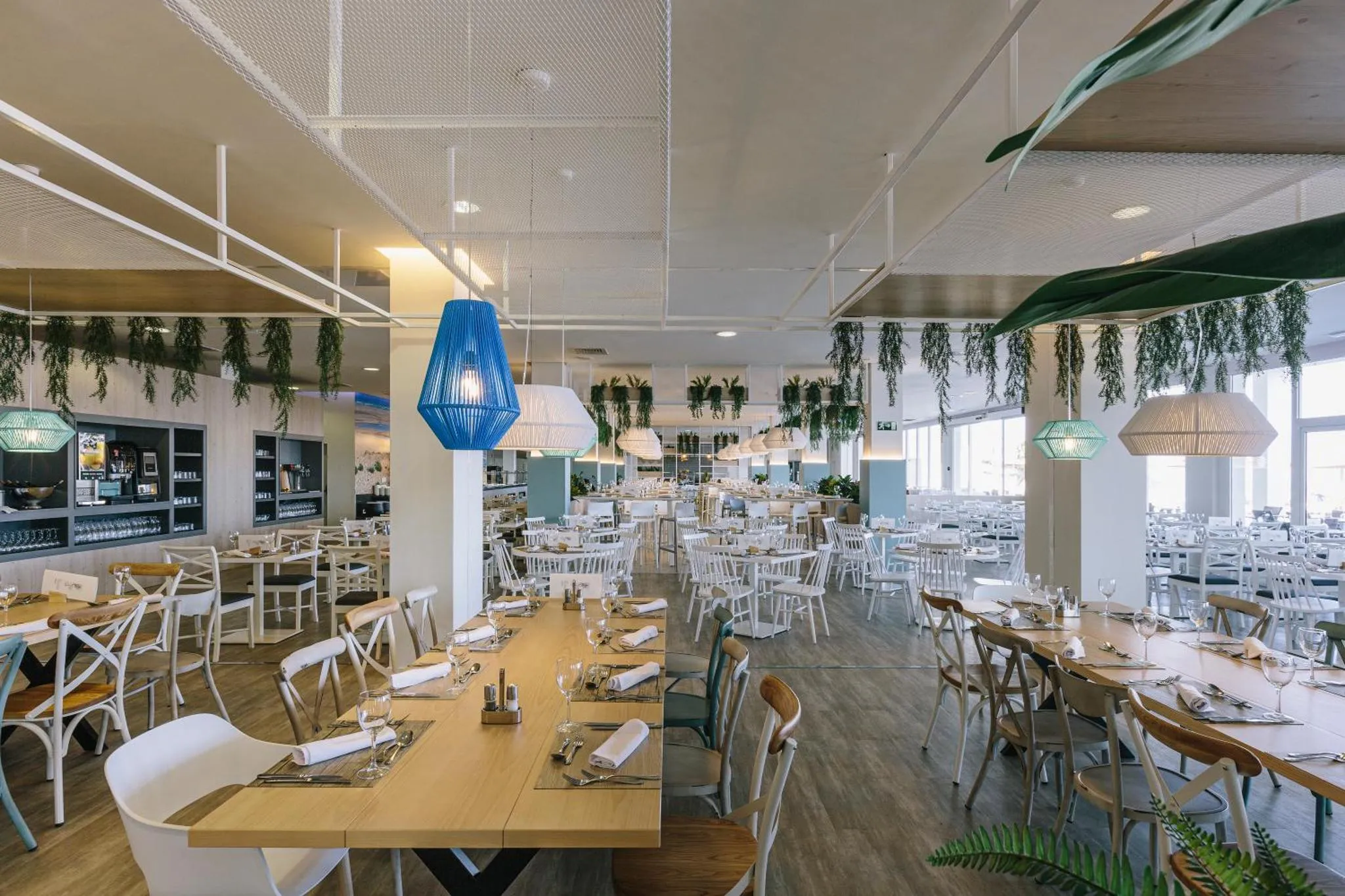 Une salle lumineuse avec de nombreuses tables dressées pour un repas.