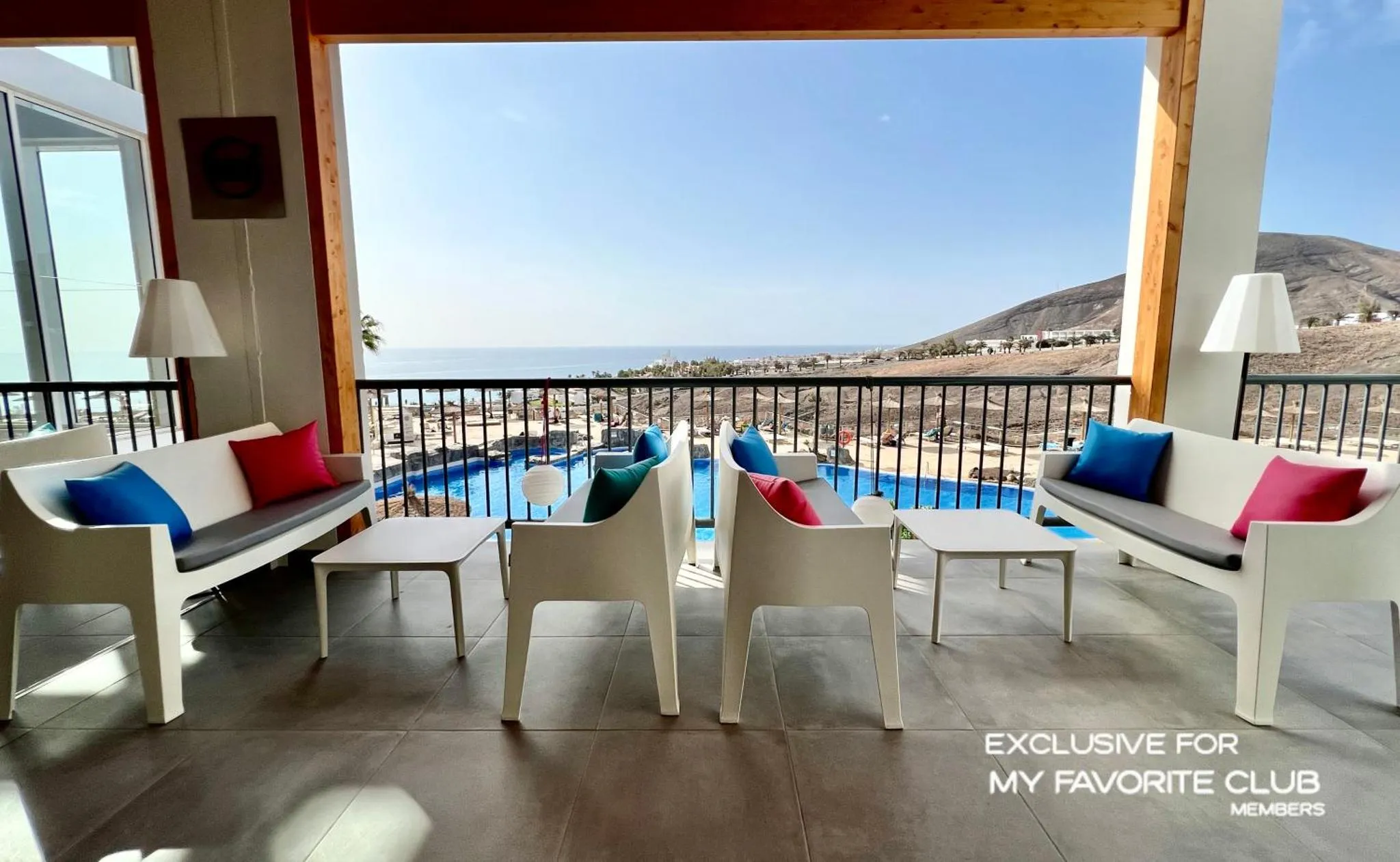 Espace de détente extérieur avec mobilier blanc et vue sur la mer.