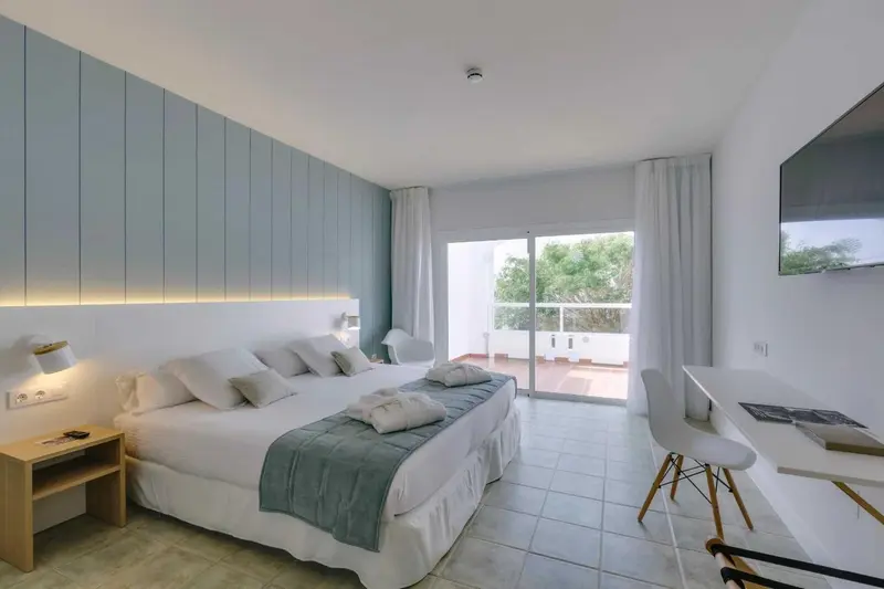 Une chambre lumineuse avec un grand lit et un accès à un balcon.