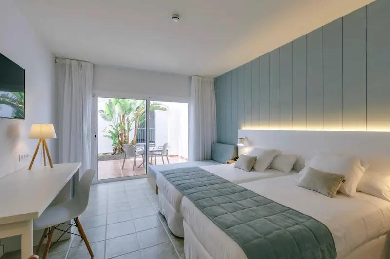 Une chambre lumineuse avec un grand lit et un accès à une terrasse.