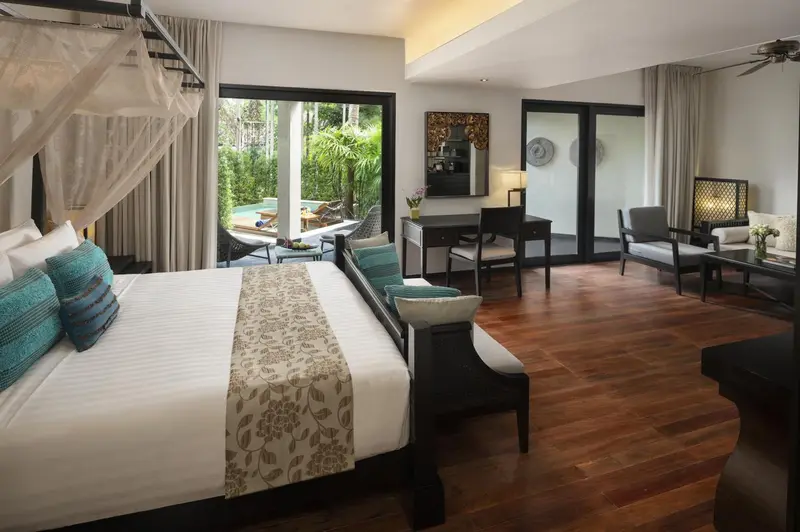 Une chambre lumineuse avec un grand lit et un espace salon.