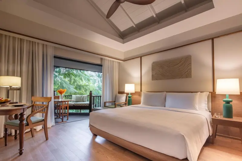 Une chambre lumineuse avec un grand lit et un coin salon donnant sur une terrasse.