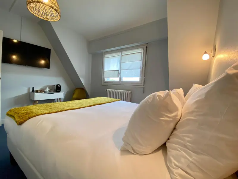 Une chambre lumineuse avec un lit recouvert d'une couverture jaune et un bureau.