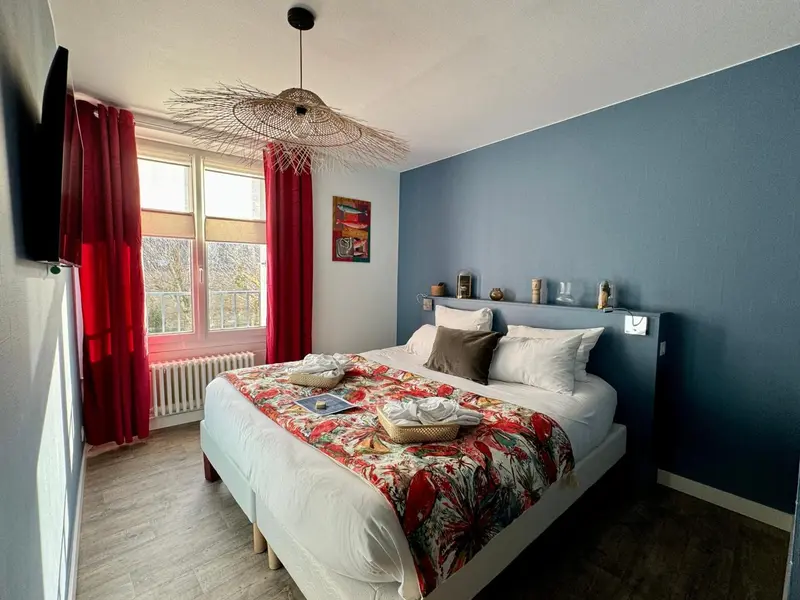 Une chambre lumineuse avec un grand lit et des rideaux rouges.