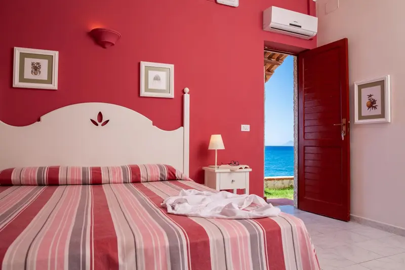 Une chambre lumineuse avec un lit recouvert d'une couverture rayée et une vue sur la mer.
