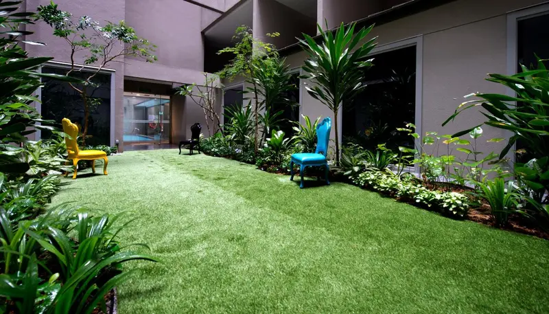 Un espace extérieur verdoyant avec des fauteuils colorés et une végétation luxuriante.