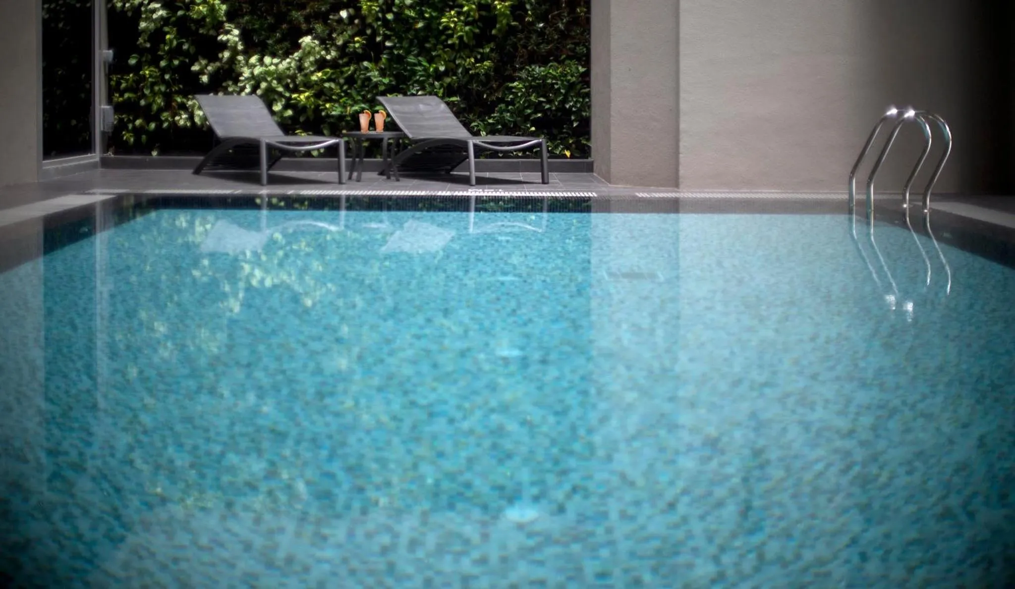 Une piscine rectangulaire avec des transats sur une terrasse.