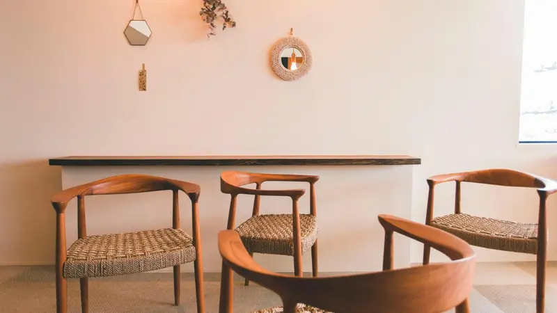 Trois chaises en bois et assises en fibres naturelles sont disposées devant une console en bois.