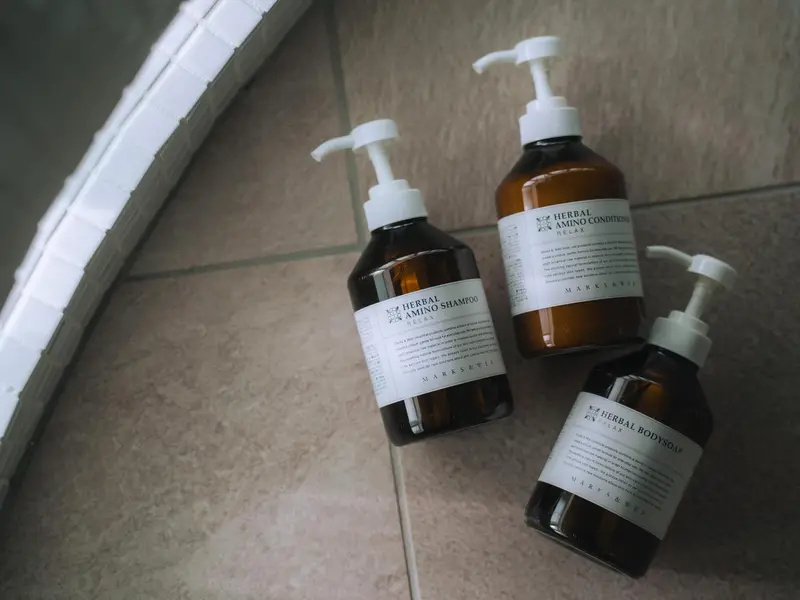 Trois flacons de produits de toilette sur un comptoir carrelé.